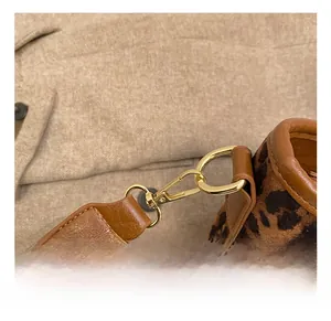 Close-up of gold metal spring hook and leopard print fabric detail on a luxury handbag