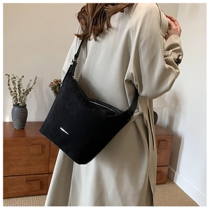 Detail of black frosted suede crossbody bag with silver lettering on an adjustable strap