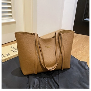 Detalle de bolso tote marrón de cuero granulado con texto de logotipo dorado