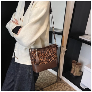 Detail of leopard print crossbody bucket bag with adjustable brown leather strap on model