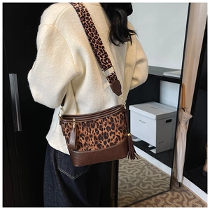 Close-up of leopard print bucket bag with leather tassels and wide shoulder strap detail