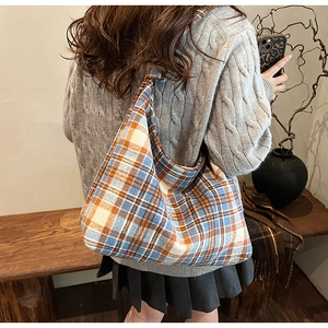 Macro shot of a plaid hobo tote bag in orange and blue worn by a model in autumn