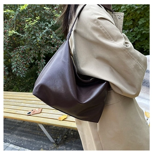 Close-up of deep brown leather hobo bag with gold zipper shown on model in park