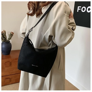 Detail of black matte suede hobo bag with adjustable silver buckle on model in trench coat