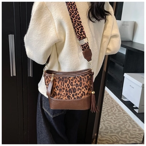 Close-up of leopard print crossbody bag with wide strap and decorative tassel
