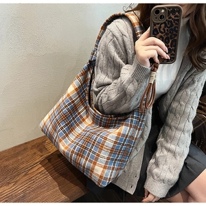 Detail view of large checkered tote bag showing blue and orange plaid fabric texture