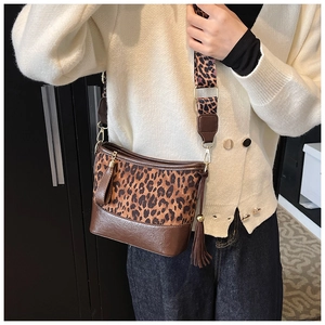 Detail of leopard print bucket bag with brown leather trim and wide adjustable strap