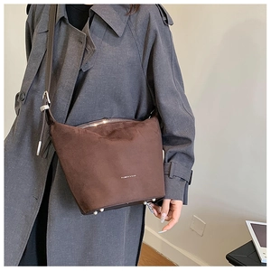 Detail view of dark brown faux suede bucket bag with metal feet and zip closure