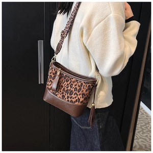 Detail of leopard print crossbody bag with wide shoulder strap and leather tassel accent