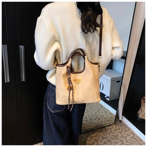 Détail du sac cabas beige montrant le similicuir texturé et la plaque décorative en métal