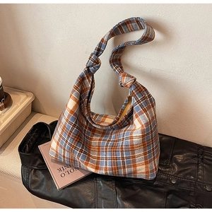 Detail of checkered tweed shoulder bag featuring a knotted strap and autumn texture