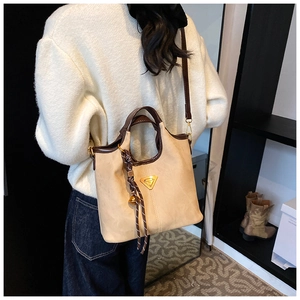 Détail du sac cabas beige montrant les coutures, les poignées en cuir marron et le logo en métal