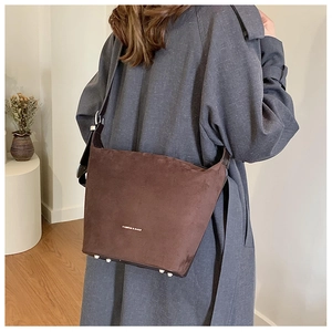 Detail view of dark brown frosted leather bucket bag with metal protective feet on bottom