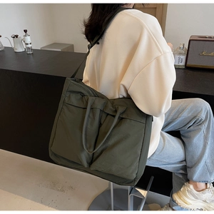 Detailed back view of model wearing an olive green nylon tote with adjustable wide strap
