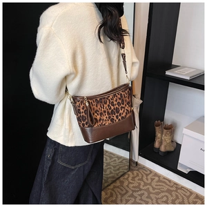 Close-up of leopard print bucket bag with wide strap styled on a fashion model