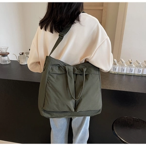 Detail of a large dark green canvas tote bag showing the textured fabric and strap