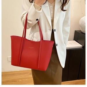 Detalle de bolso tote rojo en cuero granulado con elegante logotipo dorado en relieve