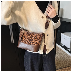 Detail of leopard print crossbody bag with wide strap and brown tassel accessory