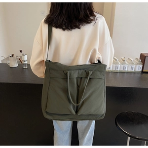 Model wearing dark green large nylon tote bag in a cozy cafe setting for daily commute