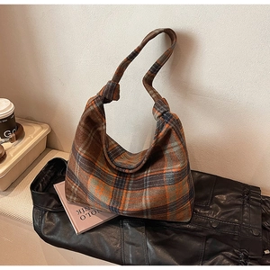 Detail of classic plaid tote bag featuring a stylish knotted shoulder strap design