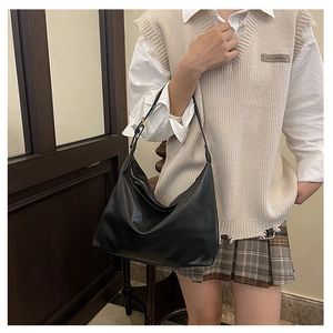 Detailed view of the black large hobo shoulder bag worn by model in a soft lighting