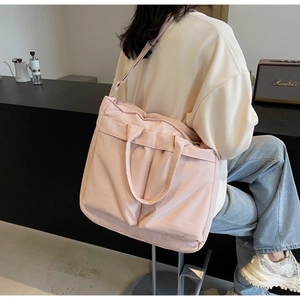Detailed view of pink nylon tote bag showing multiple pockets and adjustable shoulder strap