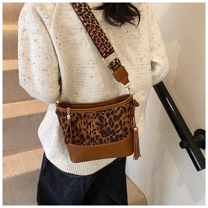 Close-up of leopard print bucket bag with wide shoulder strap and side tassel detail