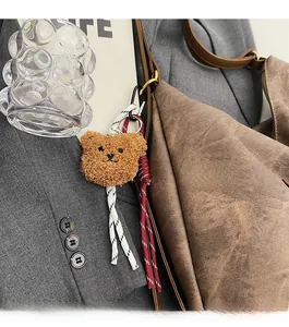 Close-up of brown plush bear charm with woven ropes on a retro shoulder bag detail