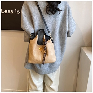 Détail du sac cabas beige et noir élégant avec logo triangle doré et bandoulière fine
