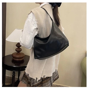 Side view of a large black hobo shoulder bag worn in a vintage indoor setting