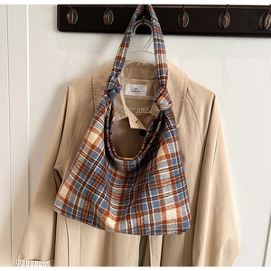 Close-up of plaid tote bag showing unique knot detail on the shoulder strap and wool texture