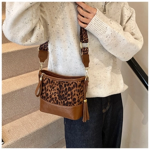 Detail of trendy leopard print bucket bag with wide shoulder strap and gold hardware