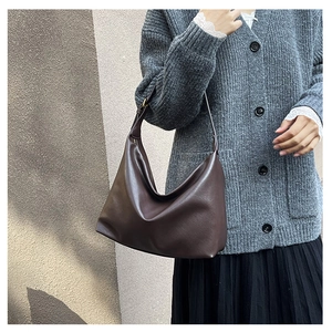 Detail of dark brown matte leather hobo bag with adjustable strap on female model