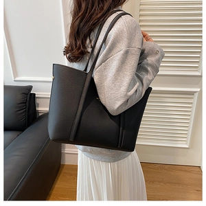 Primer plano de un bolso tote de cuero negro con textura de lichi colgado del hombro