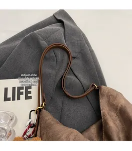 Close-up of brown corduroy shoulder bag with adjustable leather strap and gold buckle