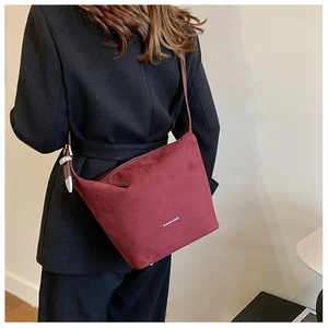 Detail of burgundy suede hobo bag featuring silver buckle and subtle logo branding