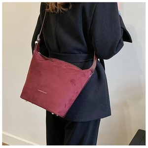 Model wearing a burgundy suede shoulder bag featuring the FASHION & BAGS logo on the back