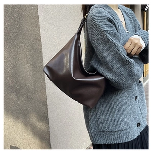 Detail of dark brown leather hobo bag with soft pleated texture and shoulder strap