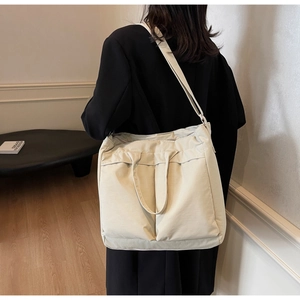 Detail of beige large capacity tote bag with front pockets and adjustable strap