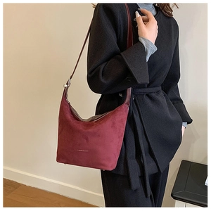 Detail shot of vintage dark red suede shoulder bag on a model wearing a black wool coat