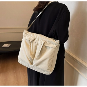 Woman wearing a large beige nylon tote bag with wide adjustable shoulder straps in style