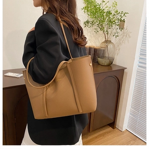 Detalle del bolso tote de cuero caqui con textura de grano y logotipo dorado