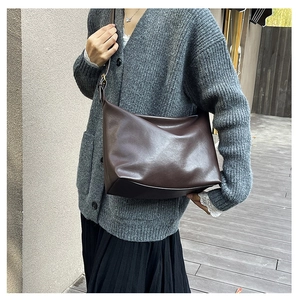 Detail of soft dark brown leather shoulder bag featuring a minimalist design and metal buckle