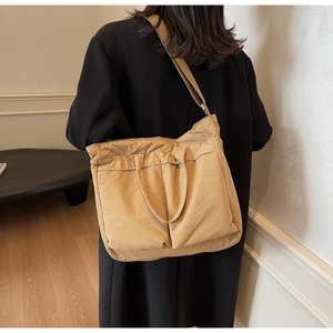 Close-up of a khaki large-capacity tote bag with two spacious front pockets on model