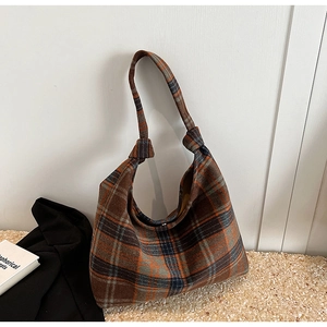 Detail of vintage plaid canvas tote bag featuring decorative knotted shoulder straps