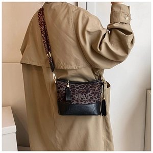 Detail of leopard print crossbody bag featuring a black fringe tassel and golden hardware
