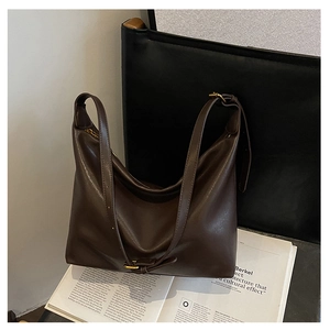 Close-up of a vintage dark brown leather tote bag with an adjustable strap and zipper