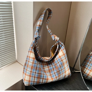 Detail of blue and orange checkered tweed tote bag with stylish knot shoulder strap design