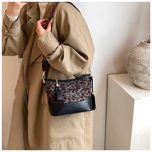 Chic leopard print bucket bag with black leather base and stylish fringe detail