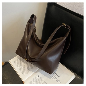 Detail of dark brown leather hobo bag with vintage gold hardware on a magazine